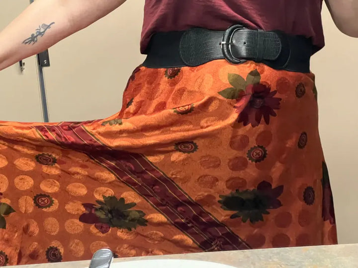 A woman's orange and maroon patterned skirt with a black belt