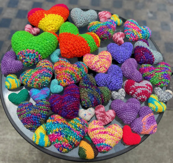 Colorful crocheted hearts in various sizes and patterns, arranged on a round table