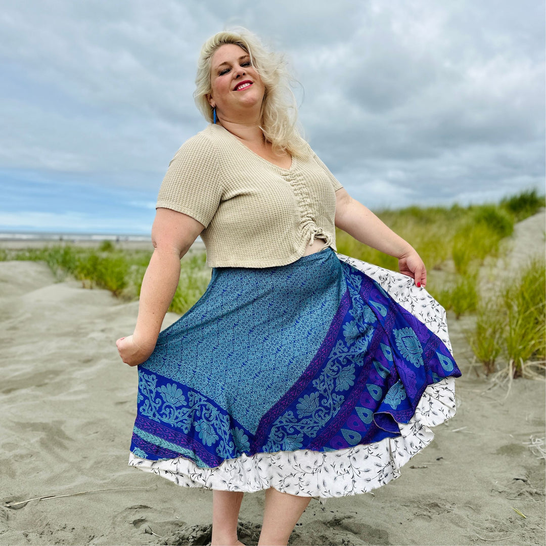 A girl wearing a tea length sari wrap skirt on a beach