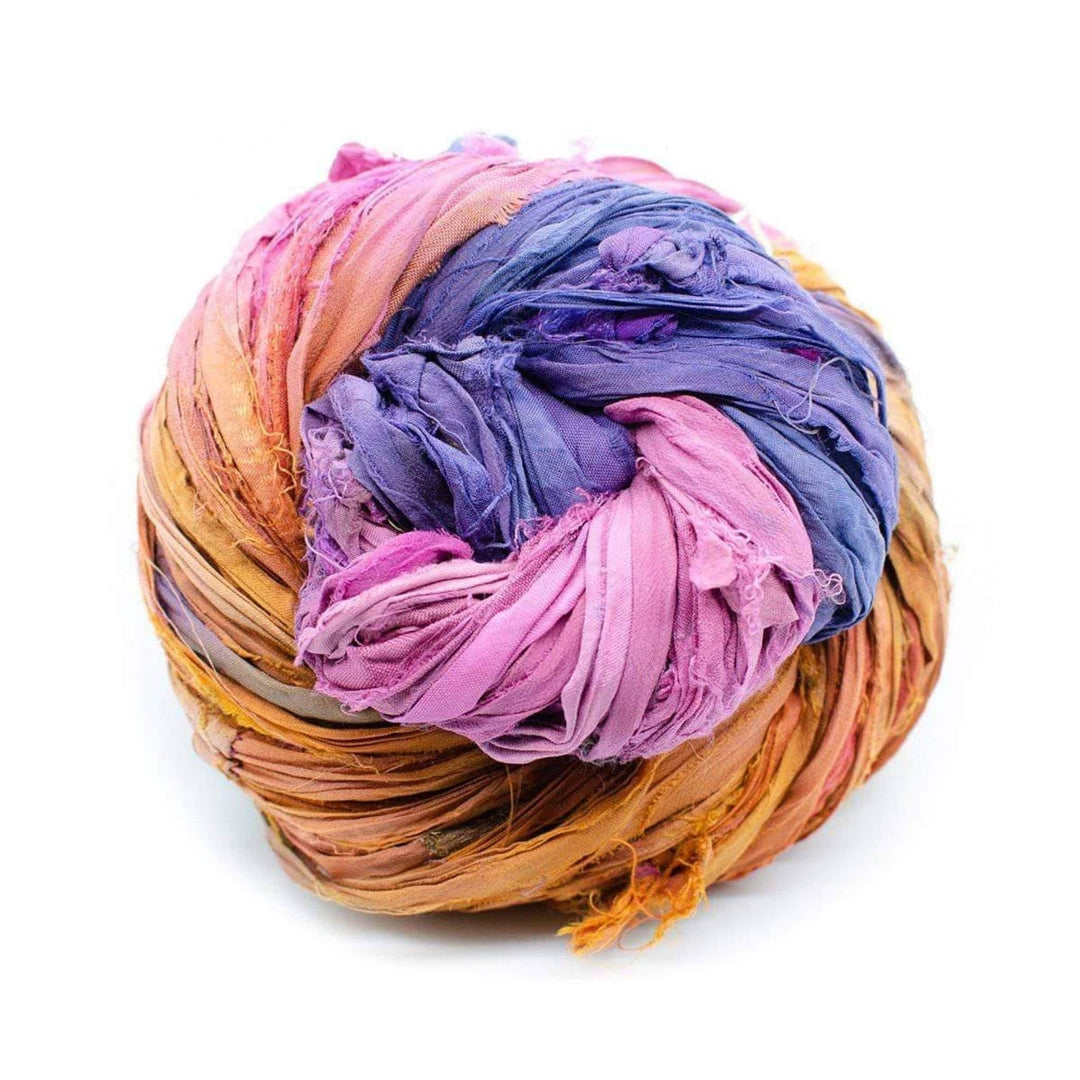 Ball of recycled sari silk ribbon in pink, purple, and orange, loosely wound on a white background.