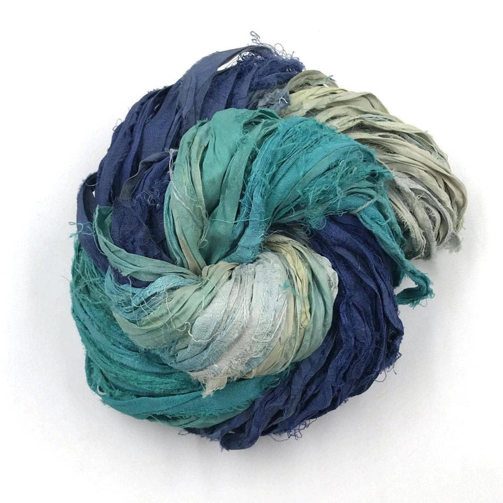 Bundle of blue, turquoise, and light green fabric strips twisted together on a white background.