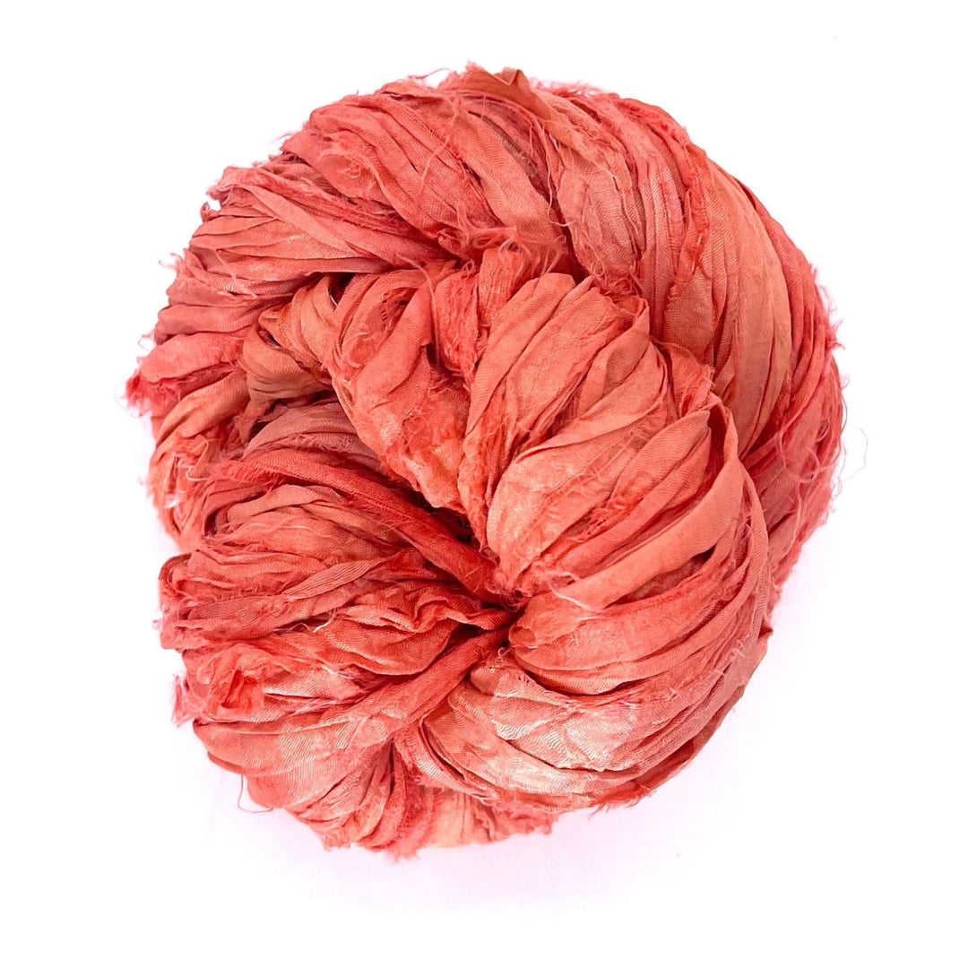 A ball of crumpled red and pink fabric on a plain white background.