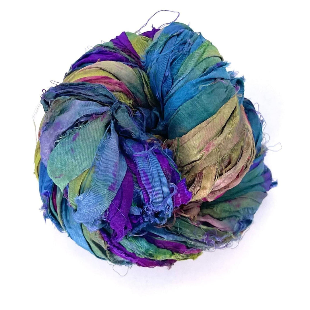 A multicolored ball of crinkled silk ribbons in blue, green, purple, and pink shades.