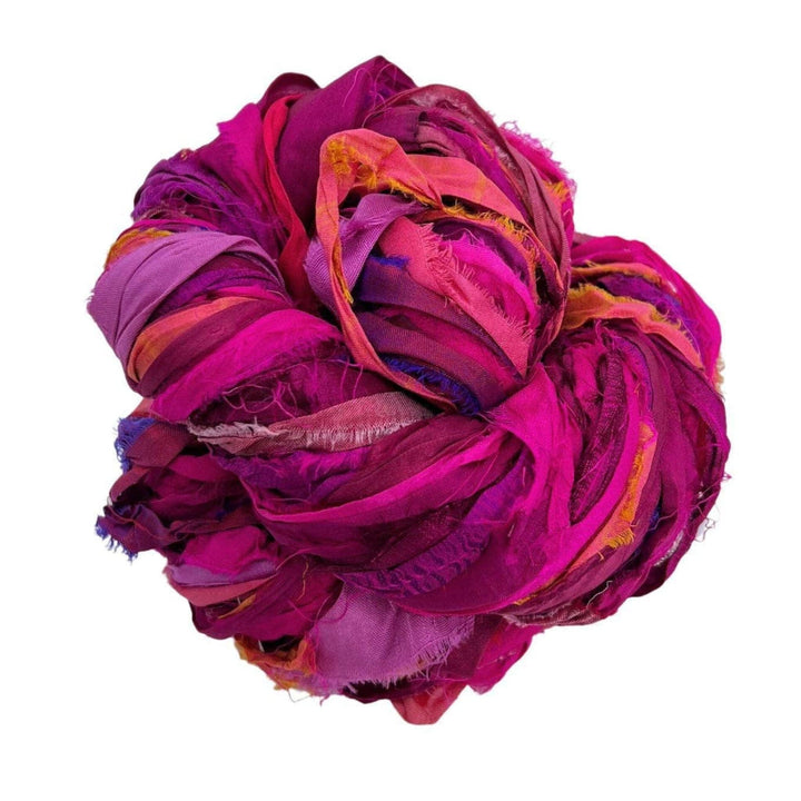 Tightly balled bundle of colorful frayed fabric strips in pink, purple, and red.