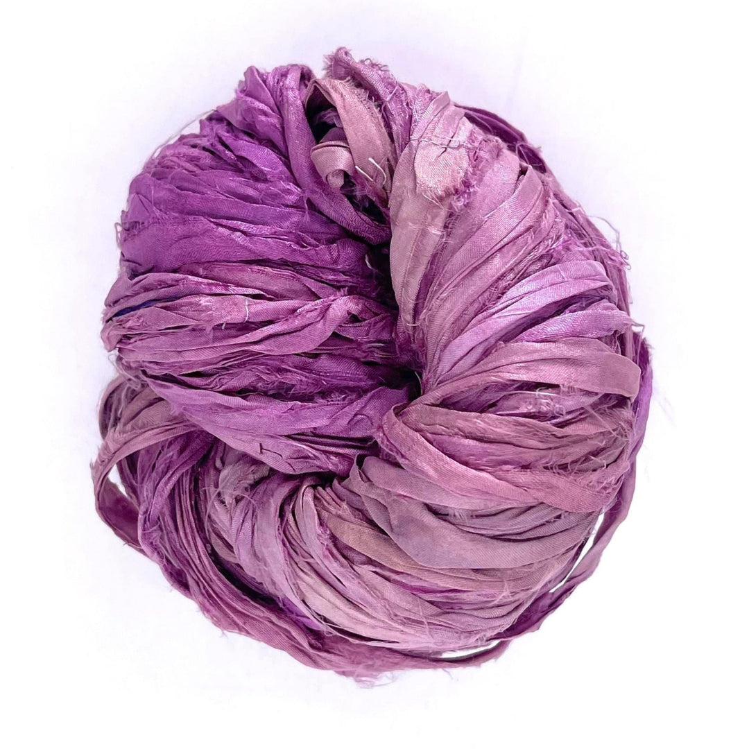 A ball of mixed purple ribbon yarn against a white background.