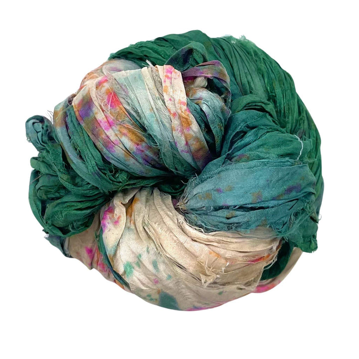 A ball of green and white crumpled fabric with hints of pink and other colors.